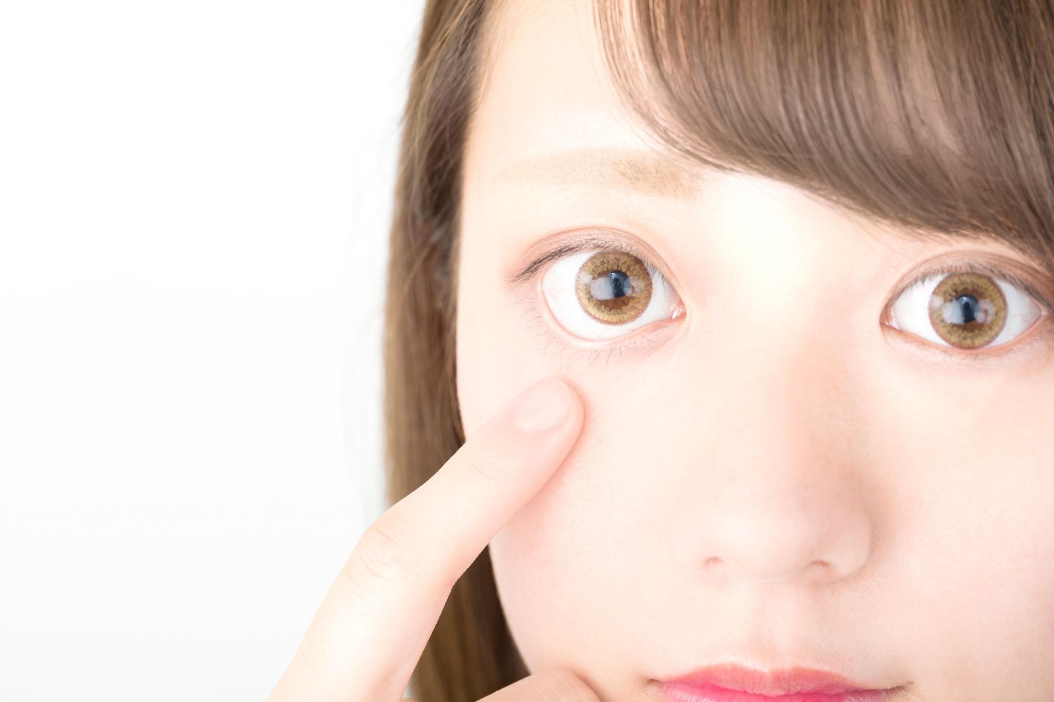 下まぶたを押さえている20代女性