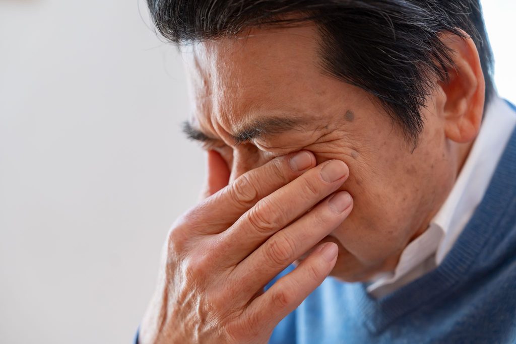 目を押さえる高齢男性