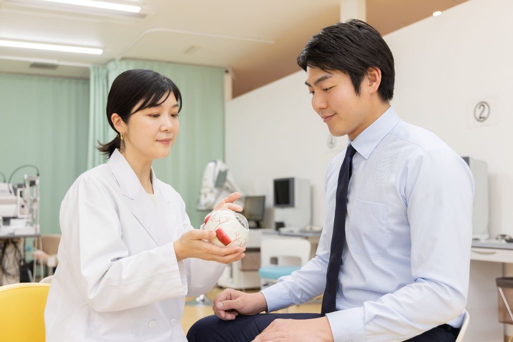 目の模型を持って患者に説明している眼科医