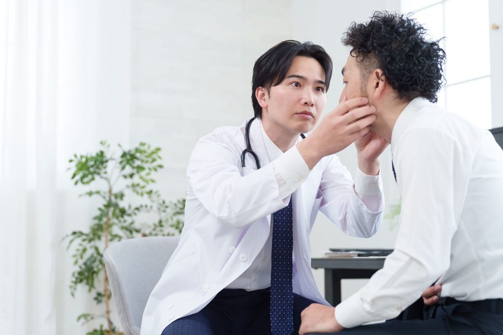 男性の目を調べている眼科医